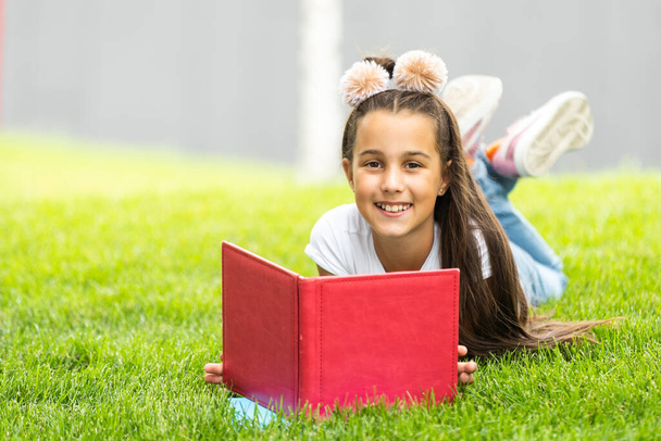 Little girl reading a book in the spring park. - Fotografie, Obrázek