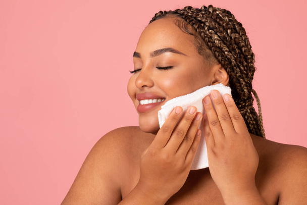 Πορτρέτο της ευτυχούς Αφρικής American Lady Drying Face με μαλακό Πετσέτα φροντίδα για το δέρμα Posing πάνω από ροζ φόντο στούντιο. Περιποίηση προσώπου και φροντίδα προσώπου - Φωτογραφία, εικόνα