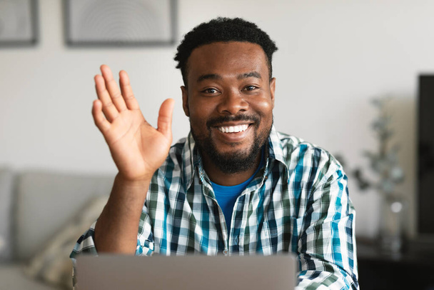 Hello. Happy Black Freelancer Guy Waving Hand To Camera Sitting At Laptop Computer Video Calling Communicating Online At Home. Remote Job And Communication Concept - Φωτογραφία, εικόνα