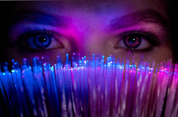 Female looks through futuristic teal coloured bokeh millennial, woman girl looking at camera with advanced fiber optic technology, Christmas - Photo, Image