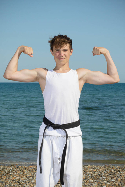 A 17 Year Old Teenage Black Belt Flexing His Muscles on A Beach - Foto, afbeelding
