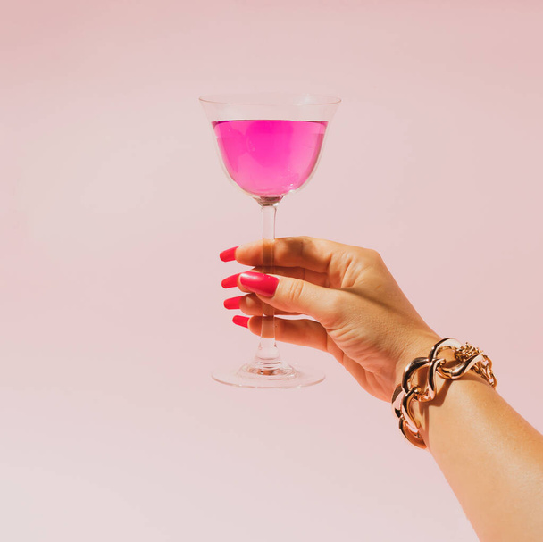 Close up female hand holding glass of pink cocktail, alcohol.Hand with gold bracelet, glamour and romantic concept - Foto, imagen
