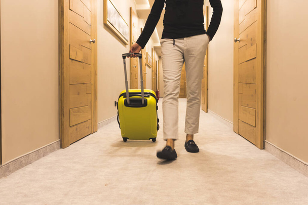 Unrecognizable man with suitcase walking through hotel hallway.  - Zdjęcie, obraz