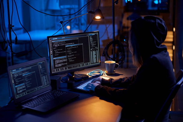 cybercrime, hacking and technology concept - female hacker in dark room writing code or using computer virus program for cyber attack - Фото, изображение