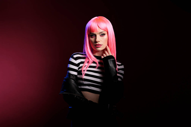 Confident pretty girl with pink hair looking at camera, expressing natural emotions and rocker punk fashion style. Wearing biker leather jacket with funky hairstyle, feeling modern and stylish. - Photo, Image