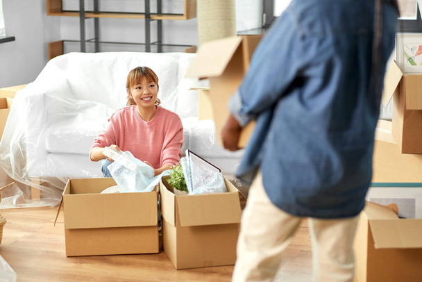 moving, people and real estate concept - women unpacking boxes at new home - Photo, image