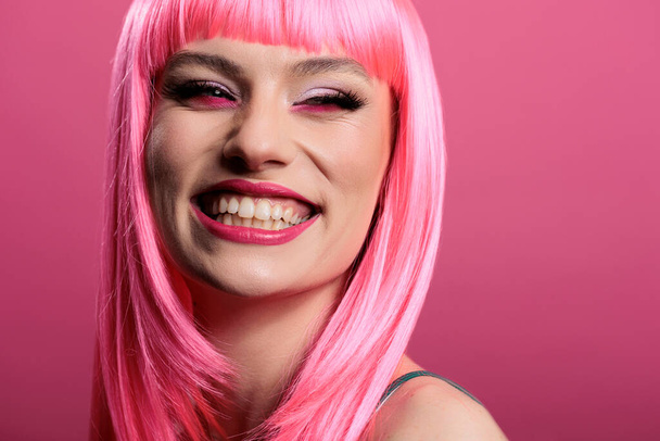 Portrait of sexy woman showing candid perfect smile on camera, feeling happy and positive. Model smiling and having white teeth, wearing beautiful makeup and pink hair wig to feel pretty. - 写真・画像