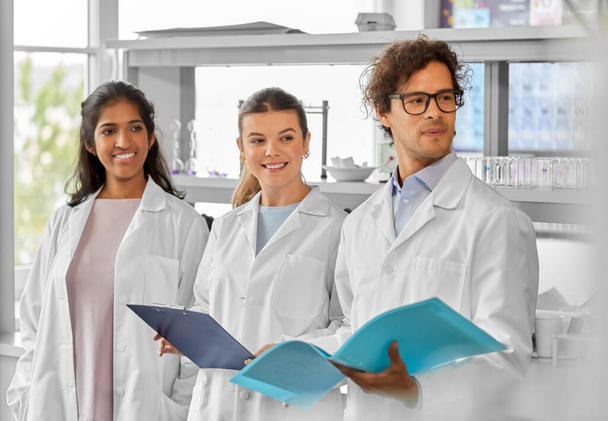 science, work and people concept - international group of happy scientists in laboratory - 写真・画像