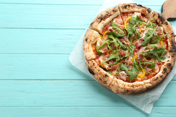 Tasty pizza with meat and arugula on light blue wooden table, top view. Space for text - Fotó, kép