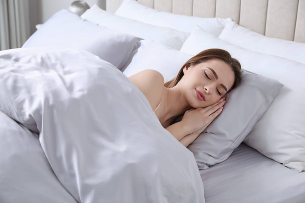Young woman sleeping in comfortable bed with silky linens - Foto, Imagem