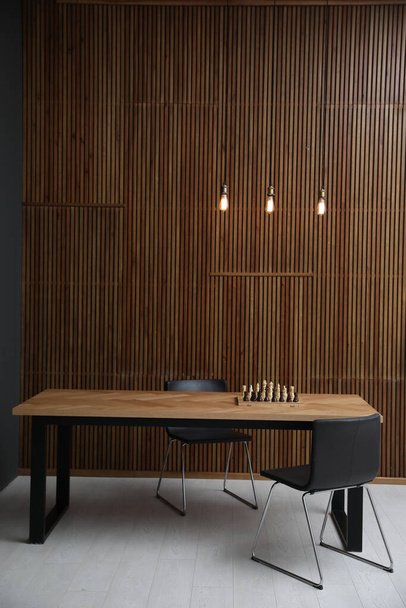 Modern table with chess near wooden wall - Photo, image
