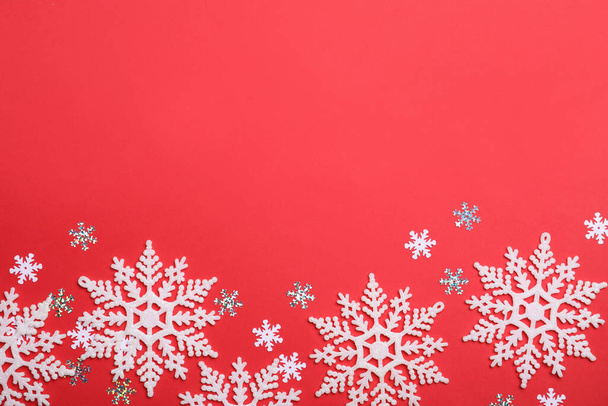 Beautiful decorative snowflakes on red background, flat lay. Space for text - Foto, imagen