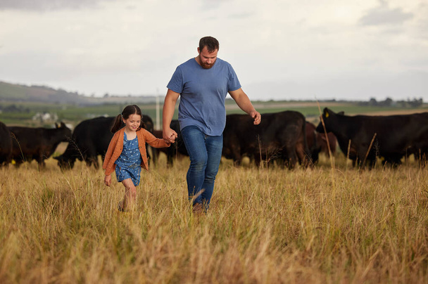 Αγρότης πατέρας, παιδί ή οικογένεια με αγελάδες σε αγρόκτημα, γρασίδι ή εξοχή. Αειφορία ή περιβαλλοντικός μπαμπάς και κορίτσι με βοοειδή στο παρασκήνιο για τον κλάδο του κρέατος, του βοείου κρέατος ή της γεωργίας. - Φωτογραφία, εικόνα