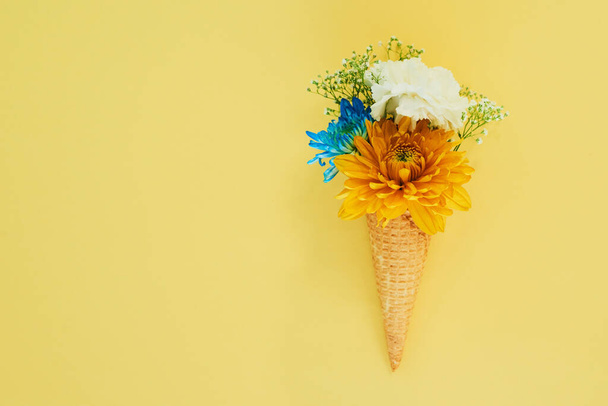 Κάποια πράγματα μας ενθουσιάζουν για το καλοκαίρι. ένα κώνο γεμιστό με λουλούδια σε ένα πολύχρωμο φόντο - Φωτογραφία, εικόνα