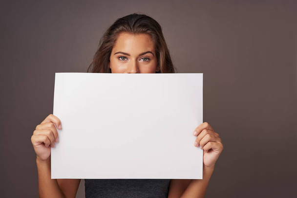 For your eyes. Studio shot of an attractive young woman holding a blank placard against a gray background - Foto, imagen