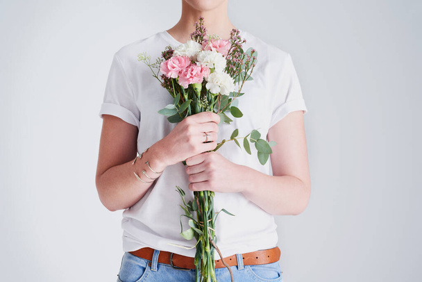 I want to feel free as the flowers. Studio shot of an unrecognizable woman holding a bouquet of flowers against a grey background - Foto, afbeelding