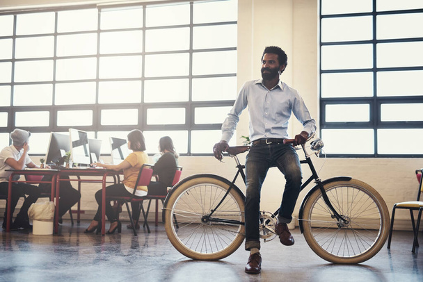 This is how I am never late. a handsome man on a bicycle in a modern office - Фото, зображення