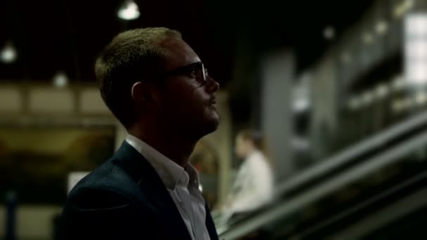 Empresario con gafas subiendo escaleras mecánicas
 - Metraje, vídeo