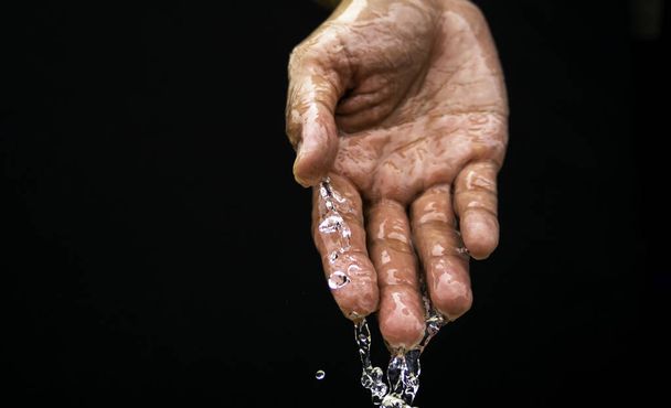 Το νερό ρέει στην παλάμη του χεριού κάτω. Η καθαρότητα του νερού.Τα οφέλη του νερού. συνθήκες ξηρασίας και φυσικές καταστροφές. - Φωτογραφία, εικόνα