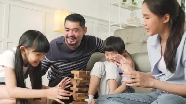 Ευτυχισμένη ασιατική όμορφη ταϊλανδέζικη οικογενειακή δραστηριότητα, γονείς, μπαμπάς, μαμά, και τα παιδιά να διασκεδάσουν παίζοντας και χαρούμενη ξύλινα μπλοκ παιχνιδιών μαζί στο σαλόνι, Σαββατοκύριακο αναψυχής, και οικιακό τρόπο ζωής. - Πλάνα, βίντεο