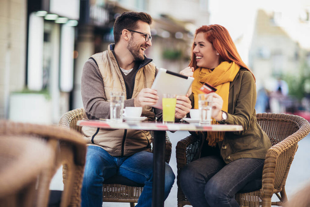 Νεαρό ζευγάρι σε ένα καφέ χρησιμοποιώντας ψηφιακή ταμπλέτα και πιστωτική κάρτα. - Φωτογραφία, εικόνα
