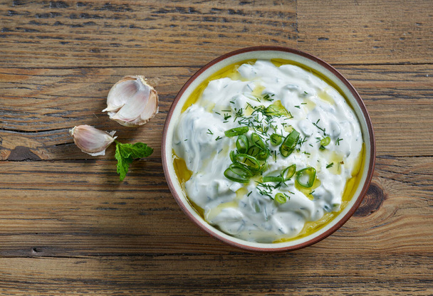bowl of sour cream or greek yogurt sauce tzatziki on wooden kitchen table, top view - Foto, Imagem