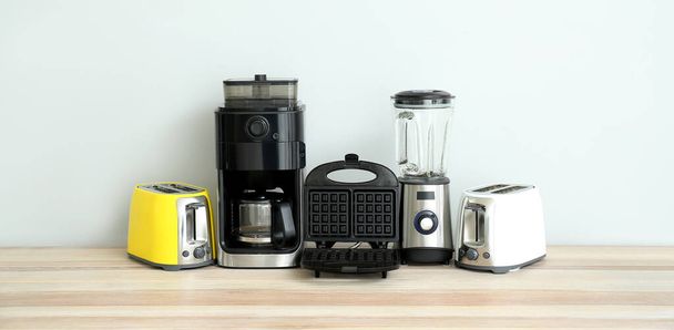 Different household appliances on table against light background  - Foto, Bild