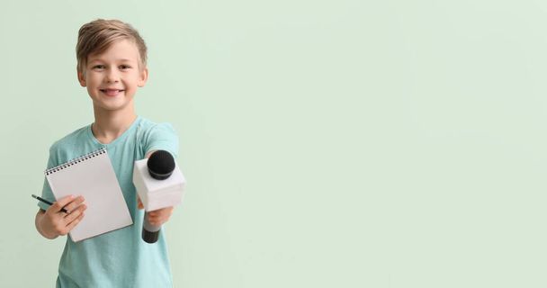 Little journalist with microphone and notebook on color background with space for text - Foto, immagini