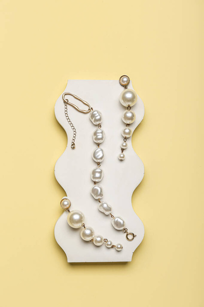 Showcase pedestal with pearl jewelry on color background - Valokuva, kuva