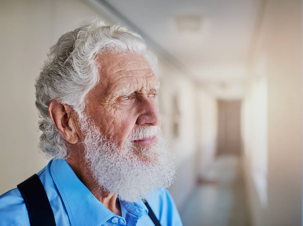 Lost in nostalgia. a senior man looking thoughtful while standing in the hallway of his nursing home - Foto, immagini
