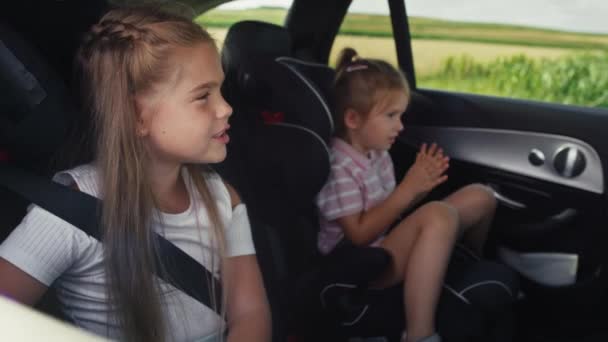 Two caucasian female children riding in the car in the back seat and singing. Shot with RED helium camera in 8K. - Záběry, video