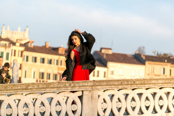 όμορφη Ιταλίδα με κόκκινο φόρεμα και μαύρο σακάκι στη γέφυρα στην πλατεία της Πάδοβας. Υψηλής ποιότητας φωτογραφία - Φωτογραφία, εικόνα