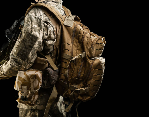 Military multicam backpack on soldier back and bags for unloading, isolated on black background - Fotó, kép