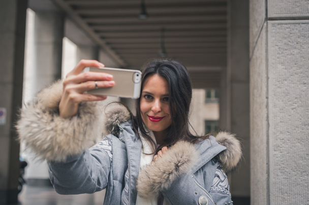 Beautiful young brunette taking a selfie in the city streets - Foto, imagen