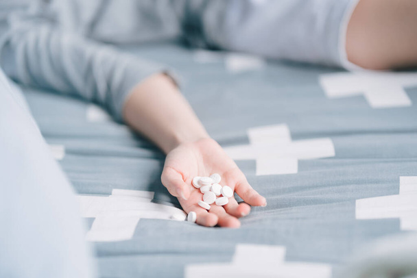 woman lying in bed with pills in hand It's a way to kill yourself with an overdose. - Fotoğraf, Görsel