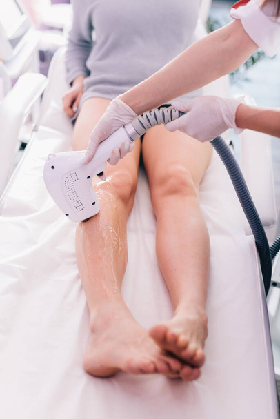 Γυναίκα σε θεραπεία αφαίρεσης τρίχας λέιζερ στο πόδι. Φροντίδα δέρματος και σώματος - Φωτογραφία, εικόνα