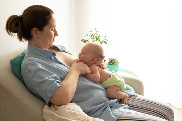 Breastfeeding in laid back position. Mothed and baby at the chair. - Photo, image