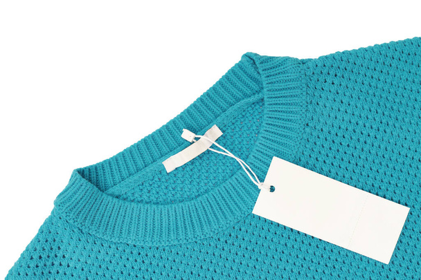White blank rectangular clothing tag, label mockup template on turquoise knitted sweater isolated on white background . Price tag label with copy space for text. Shopping, sale, discount, black friday - Foto, Bild