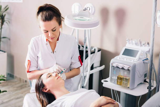 Injectable tissue stimulator on woman face in beauty salon. Aesthetic medicine - Foto, Imagen