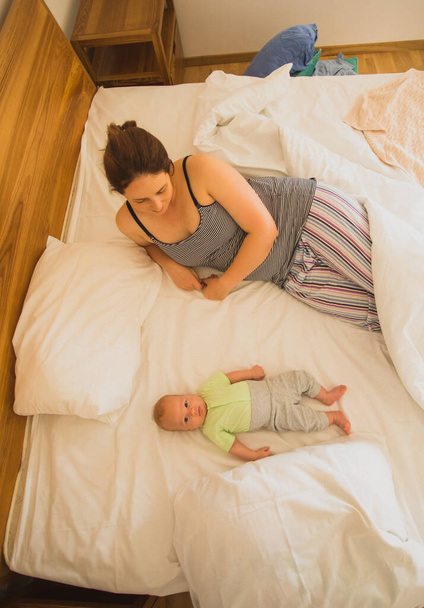 Mother and newborn baby sleep in the bed together - Foto, imagen