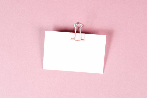 Blank white paper with a paperclip on a pink colored background, copy space for text, reminder or message in the office, communication concept - Fotoğraf, Görsel