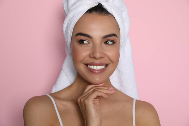 Beautiful young woman with towel on head against pink background - Photo, image