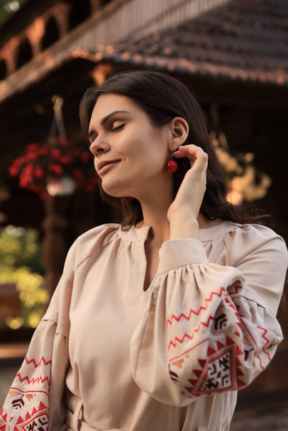 Beautiful woman wearing embroidered dress in village. Ukrainian national clothes - Fotó, kép