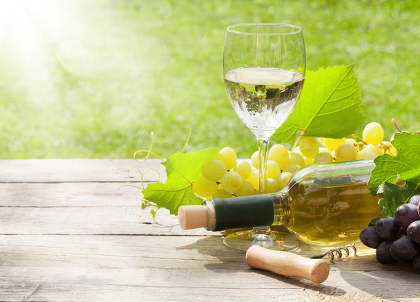 Copo de vinho branco e garrafa com cacho de uvas
 - Foto, Imagem