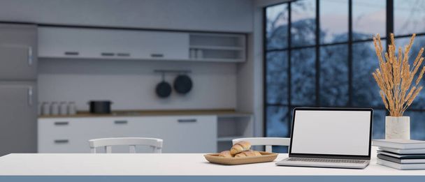 Laptop white screen mockup on a modern white dining table with book, bread basket, flower ceramic vase and copy space over blurred modern kitchen in the background. 3d rendering, 3d illustration - 写真・画像