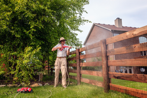 Чоловік прибирає дерев'яний паркан
 - Фото, зображення