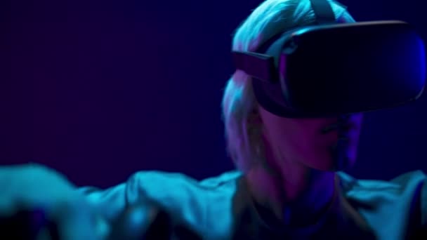 Professional gamer exploring environment in simulation closeup. Young generation z man in VR helmet using wireless controllers playing at neon light. Modern technologies and metaverse concept - Filmagem, Vídeo