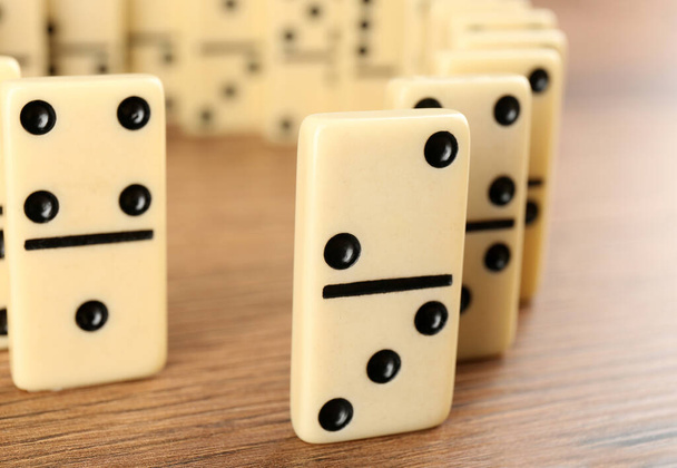 White domino tiles with black pips on wooden table, closeup - Photo, image
