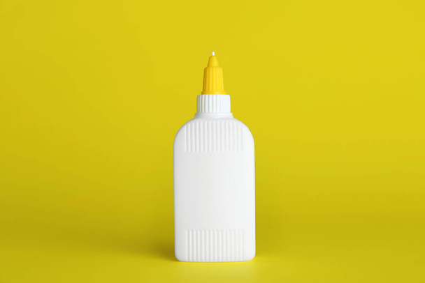 Blank bottle of glue on yellow background - Φωτογραφία, εικόνα