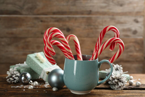 Many sweet candy canes, gift boxes  and Christmas decor on wooden table - 写真・画像